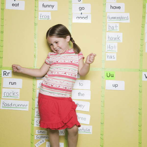 Little girl standing in front of a word wall in a classroom